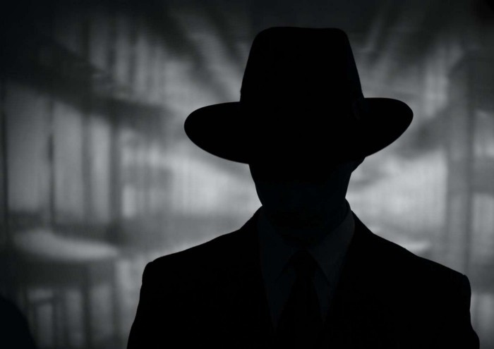 a silhouette of a man in a suit and tie against a blurred grey background